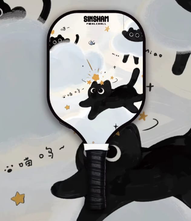 A kids' paddle ball toy with a black cat design, featuring black and white colors with some gold accents.