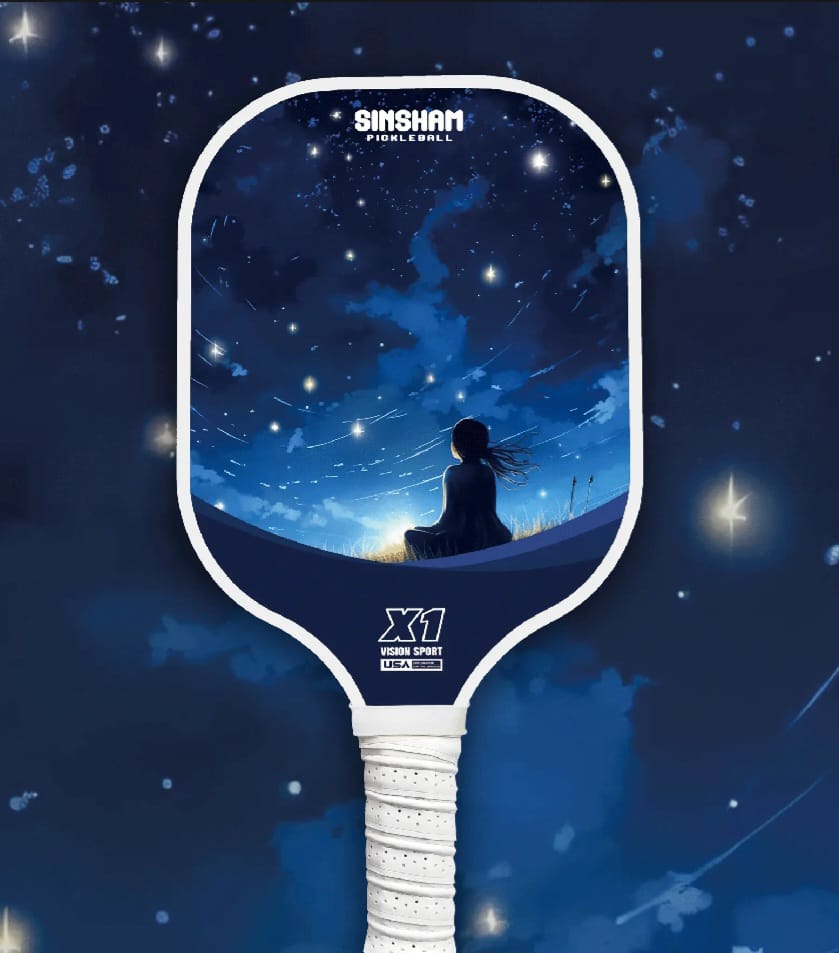 Sold as a single Pickleball paddle. Has a starry night design - A girl sitting on the grass watching the night sky with shooting stars.