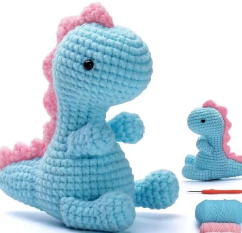Crocheted blue dinosaur with pink hair on a white background