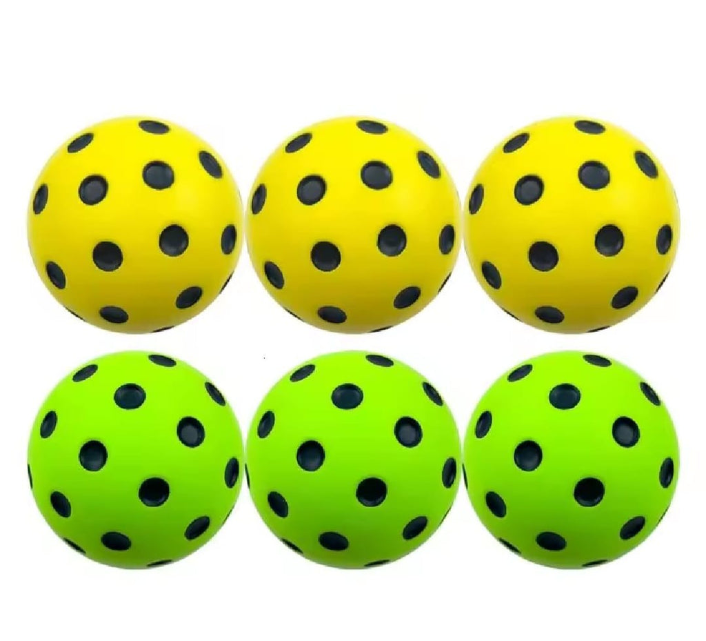 Six yellow and green soft foam pickleball balls with black holes on a white background