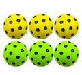 Six yellow and green soft foam pickleball balls with black holes on a white background