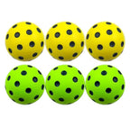Six yellow and green soft foam pickleball balls with black holes on a white background