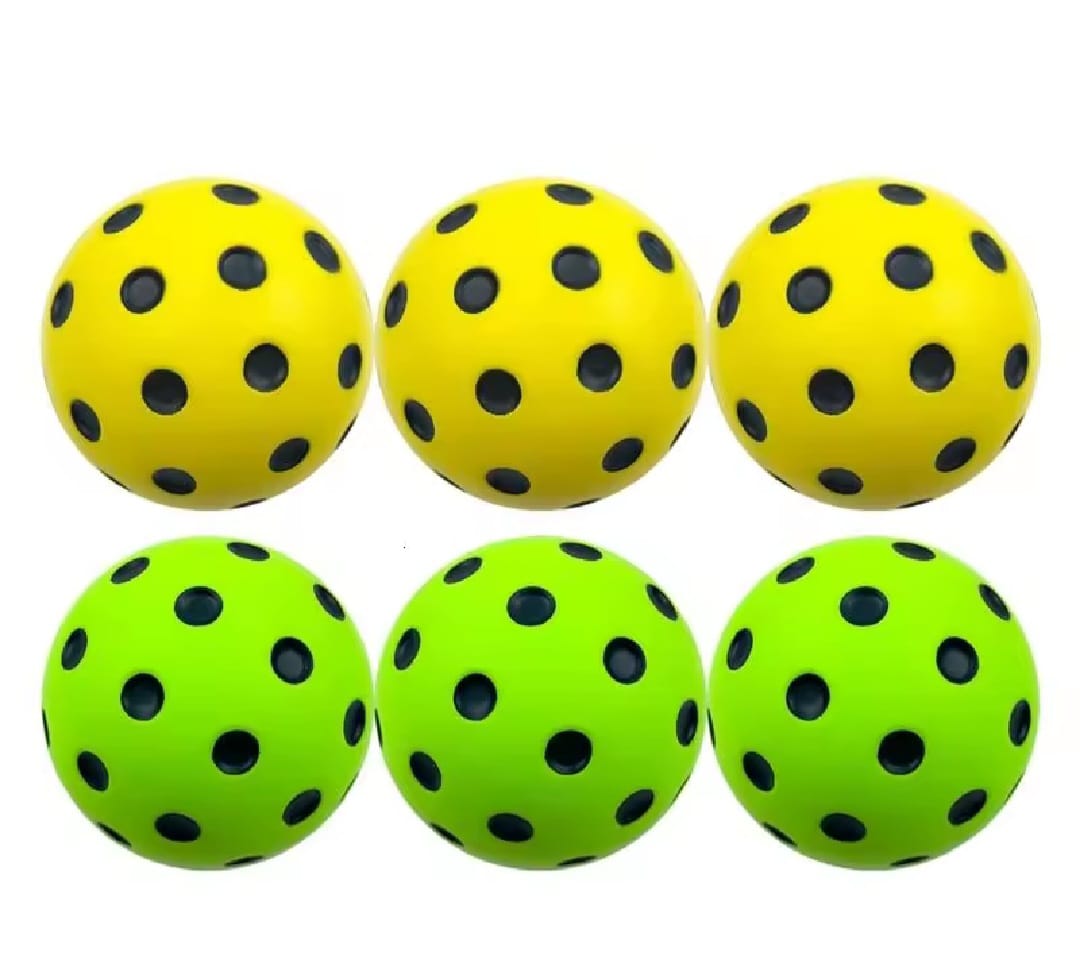 Six yellow and green soft foam pickleball balls with black holes on a white background