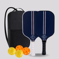 Two blue pickleball paddles with a black carrying bag and four colorful balls on a light gray background.