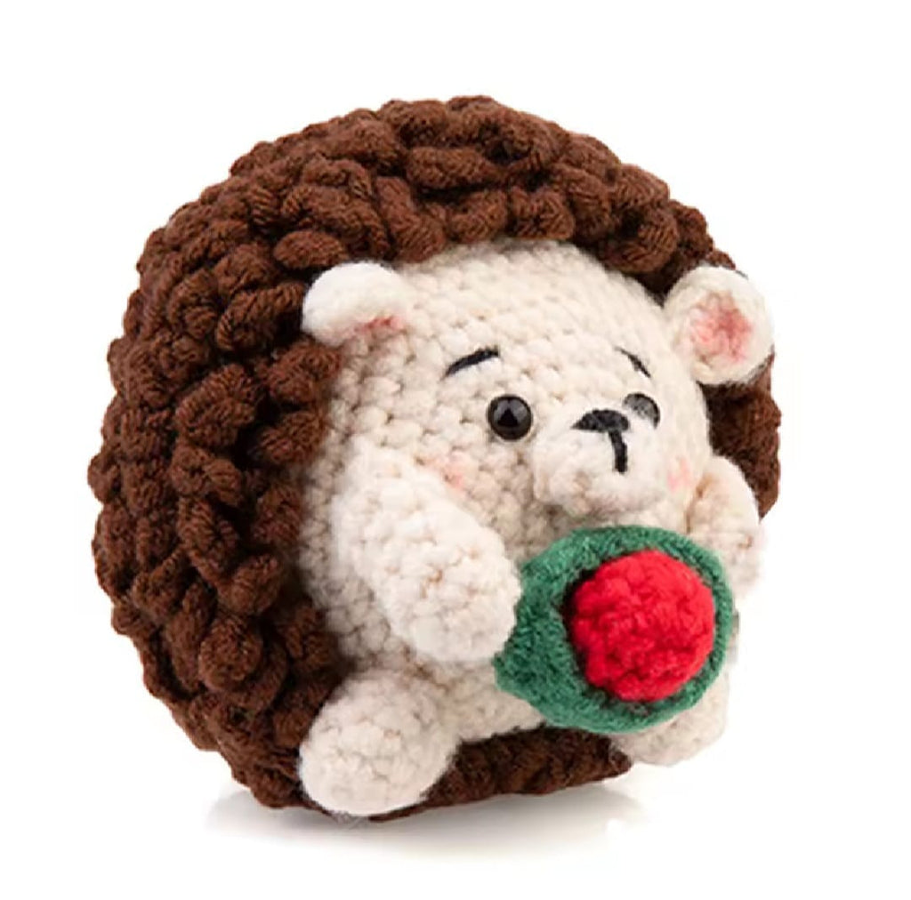 Up close photo of a crochet hedgehog holding a rose. 
