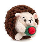 Up close photo of a crochet hedgehog holding a rose. 