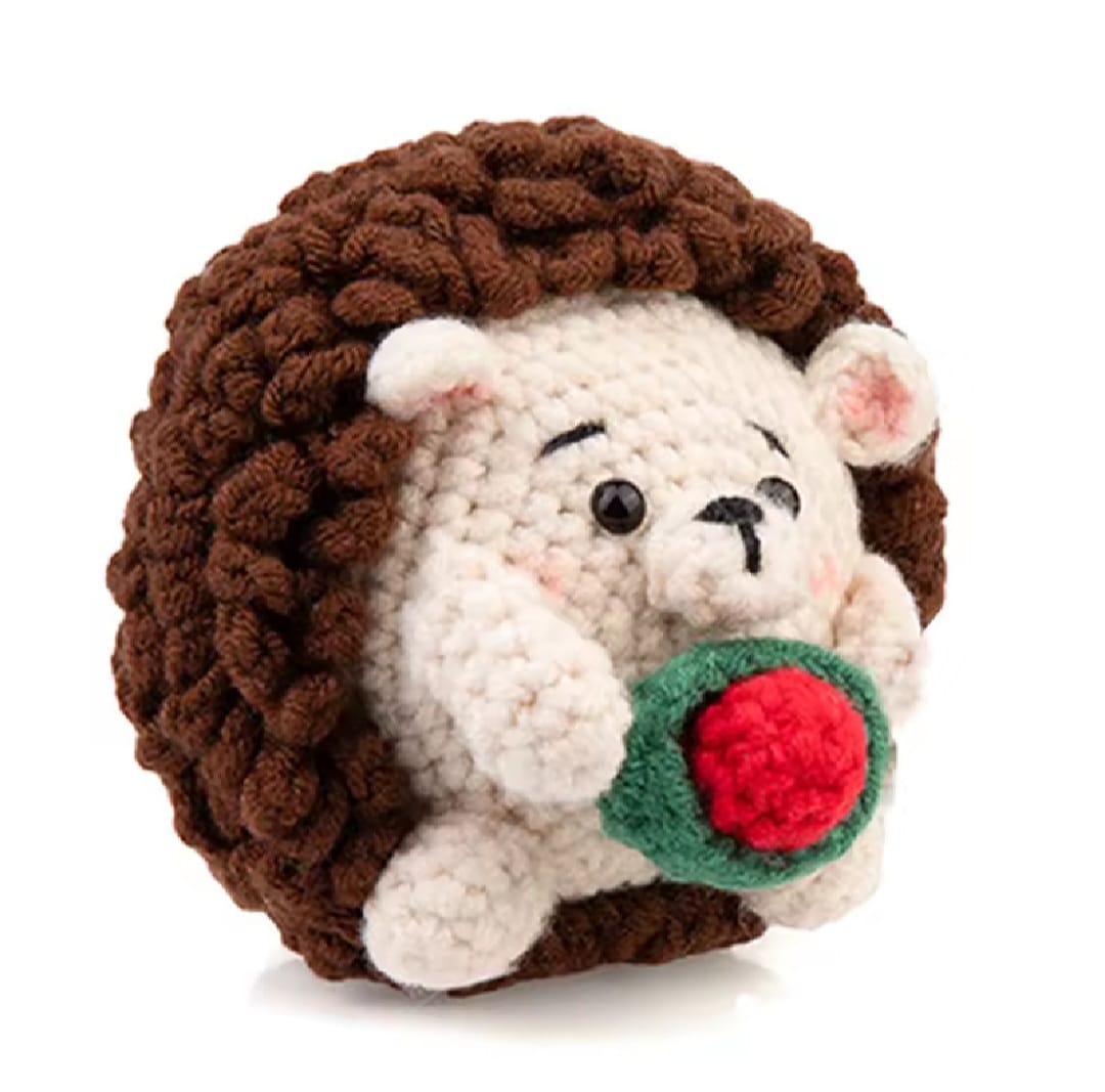 Up close photo of a crochet hedgehog holding a rose. 