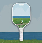 Single Pickleball Paddle with an idyllic design, a person on a bicycle on a dirt road looking at the scenery in front of him which is the grass and the sea in an artistic form.