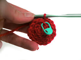 Crochet red circle with a blue marker pin marking a stitch