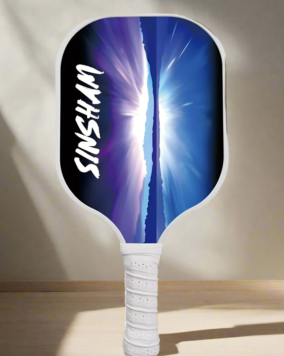 Single Pickleball Paddle with a design of a blue midnight artistic scenery of the sky, mountains and sea. 